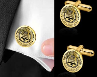 May include: Gold-toned cufflinks with the text "UNIVERSITY OF TECHNOLOGY" and "MACHINE LEARNING" in a circular design. The cufflinks are on a black background and are shown on a white shirt cuff.