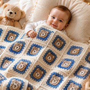 May include: A handmade crochet baby blanket featuring a repeating pattern of square motifs. Each square displays a central tan bear face surrounded by a border of blue yarn, all framed by an off-white yarn edge. The blanket has a textured finish.