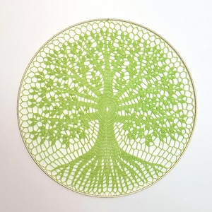 May include: A round, lime green crocheted tree design with a gold-colored metal ring. The tree features a detailed trunk, branches, and roots, all crafted with a delicate, openwork pattern. The design is centered on a white background.