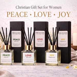 Peut inclure: Un coffret cadeau chrétien avec trois diffuseurs à roseaux étiquetés « Paix », « Amour » et « Joie ». Chaque diffuseur a un col doré, des roseaux noirs et une étiquette avec un verset biblique. Une bougie et des fleurs sont également présentes.