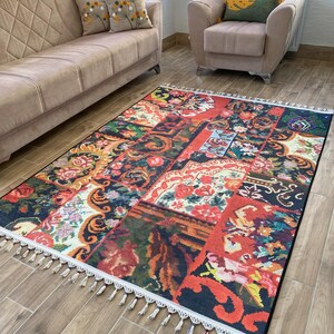 Peut inclure: Un tapis rectangulaire avec un motif patchwork. Il présente des motifs floraux et abstraits en rouge, orange, bleu et vert. Le tapis a une bordure blanche avec des glands. Il est posé sur un sol en bois. Les dimensions du tapis sont en centimètres.