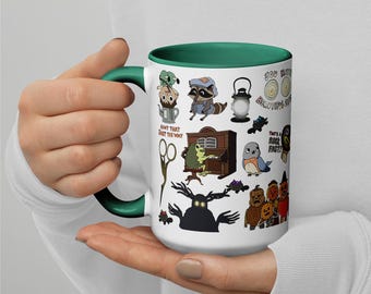 Puede incluir: Taza de cerámica blanca con asa e interior verdes. La taza está decorada con ilustraciones de dibujos animados de varias criaturas y objetos, incluyendo un mapache, una rana y una linterna. El texto incluye "Ain't that just the way" y "You make beautiful things".