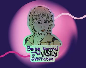 Peut inclure: Un autocollant avec une illustration de dessin animé d'une personne aux cheveux bouclés, portant un haut de couleur claire. L'autocollant porte le texte "Being Normal is VASTLY Overrated" en vert, violet et bleu, sur fond rose et violet.
