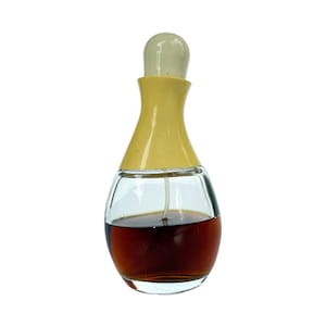 May include: A vintage perfume bottle with a clear glass body and a yellow cap. The bottle contains a dark brown liquid. The cap is a light yellow color and has a rounded top. The bottle has a classic, elegant design.
