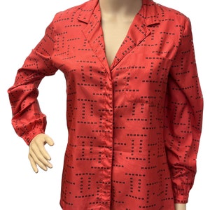 Puede incluir: Una camisa de manga larga con botones y un patrón geométrico en negro y coral.