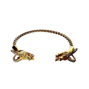 May include: Gold-coloured cuff bracelet with a twisted rope design. The bracelet features detailed ram head accents on each end. The open design allows for easy wear. A unique piece of jewellery.