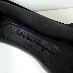 May include: Close-up of the sole of a black shoe. The embossed text "Salvatore Ferragamo" and "MADE IN ITALY" are visible. The shoe's sole shows signs of wear.