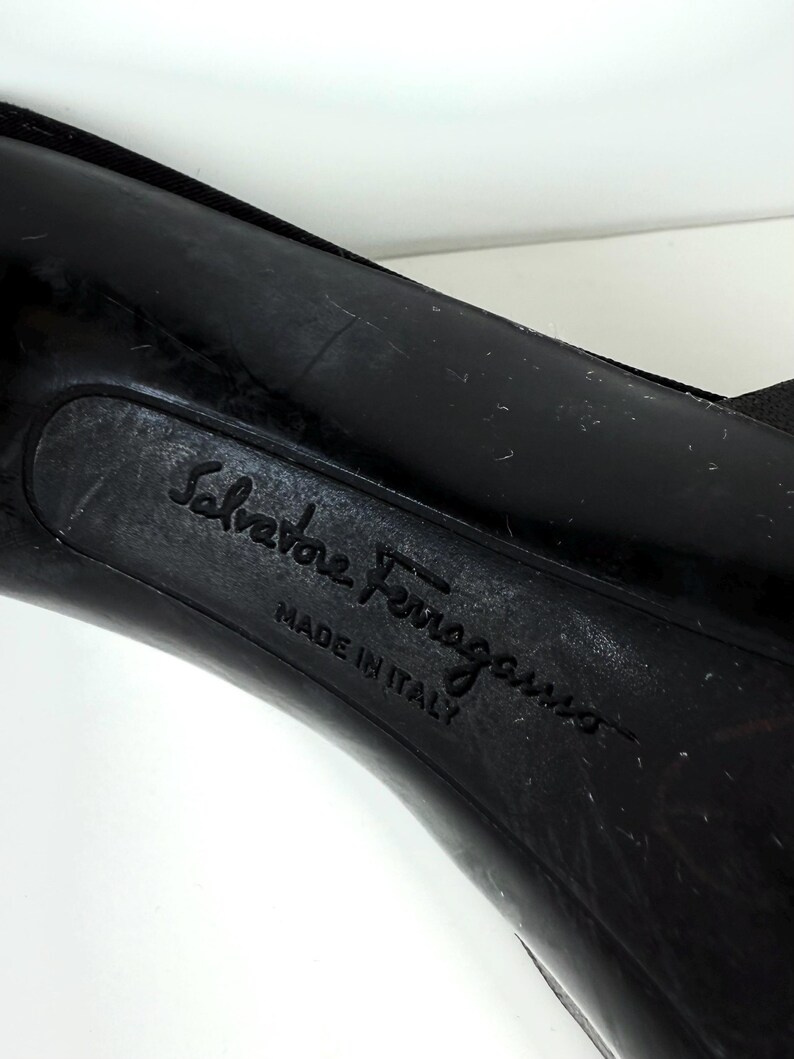 May include: Close-up of the sole of a black shoe. The embossed text "Salvatore Ferragamo" and "MADE IN ITALY" are visible. The shoe's sole shows signs of wear.