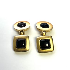May include: A pair of gold tone earrings with black oval and square shaped stones.