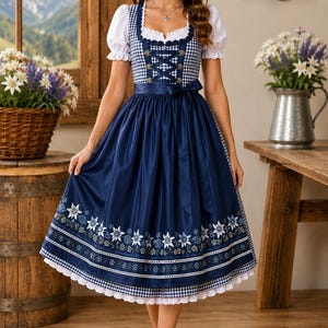 May include: A navy blue and white gingham dirndl dress featuring a white blouse with puffed sleeves, a lace-up bodice with metal hooks, a satin ribbon waist tie, and a skirt adorned with a floral edelweiss pattern and a white lace hem trim.