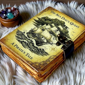 Könnte beinhalten: Ein Tagebuch im Vintage-Stil mit dem Titel "The Sea Dog's Quest, A Pirate's Tale". Das Cover zeigt eine detaillierte Illustration eines Schiffes auf See. Das Tagebuch hat einen Verschluss und gealterte Papierseiten. Neben dem Tagebuch befindet sich eine kleine Holzschale mit Edelsteinen.