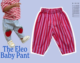 May include: The Eleo Baby Pant. Pink and red striped baby pants with an elastic waistband. The pants are shown with a matching striped shirt and white sneakers. The pants have two red strawberry appliqués. Sizes available: 0-3 months to 3T.