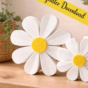 Puede incluir: Dos grandes decoraciones de margaritas blancas con centros amarillos sobre una superficie de madera. Los pétalos están en capas, dando un efecto 3D. Una pancarta amarilla en el fondo dice "digitaler Download".