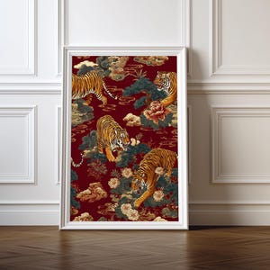 Puede incluir: Una impresión artística enmarcada con un patrón repetido de tigres, nubes y flores en tonos naranja, dorado y crema sobre un fondo rojo oscuro. La obra de arte se muestra en un marco blanco y se apoya contra una pared blanca.