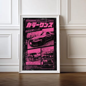 May include: Framed poster with a black and pink design featuring a car. The poster has Japanese text and a distressed, vintage aesthetic. The car is depicted in multiple views, with a focus on its sleek design.