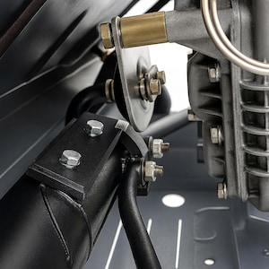 May include: Close-up of a mechanical component with a metallic finish. The image shows a combination of silver, black, and brass-colored parts, including bolts, a circular disc, and a cylindrical element. The components are assembled with precision.