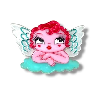 Peut inclure: Broche en forme de chérubin rose avec des cheveux bouclés rouges, de longs cils et une bouche rouge en forme de cœur. Le chérubin repose sur un nuage turquoise avec des ailes blanches et turquoise. La broche est en acrylique.