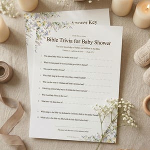 May include: A white paper Bible Trivia for Baby Shower game card featuring a floral border of blue and yellow flowers. The text includes ten questions about biblical children, a Psalm 127:3 quote, and instructions for the game.