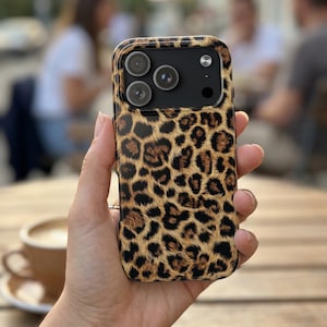 Könnte beinhalten: Smartphone-Hülle mit Leopardenmuster. Die Hülle hat ein sich wiederholendes Muster aus braunen und schwarzen Flecken. Die Handyhülle hat drei Kameralinsen.