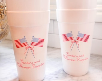 May include: White foam cups stacked in two groups. Each cup features a design of crossed American flags with red and blue stripes and the text "Sanders and Villaveces Properties" in red script.