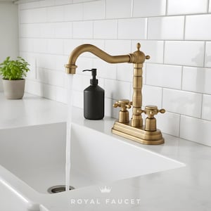 Può includere: Un rubinetto in ottone in stile vintage con un beccuccio curvo e manopole a croce. Un dispenser di sapone nero è accanto al rubinetto. L'acqua scorre in un lavandino bianco. Il testo "ROYAL FAUCET" è in basso.