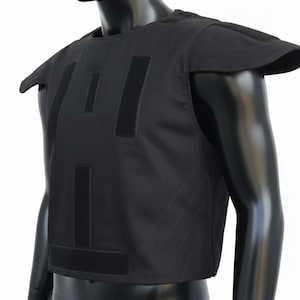May include: Black ballistic vest with shoulder pads, displayed on a black mannequin. The vest has multiple hook-and-loop closures and a quilted design on the sides. The mannequin is set against a white background.