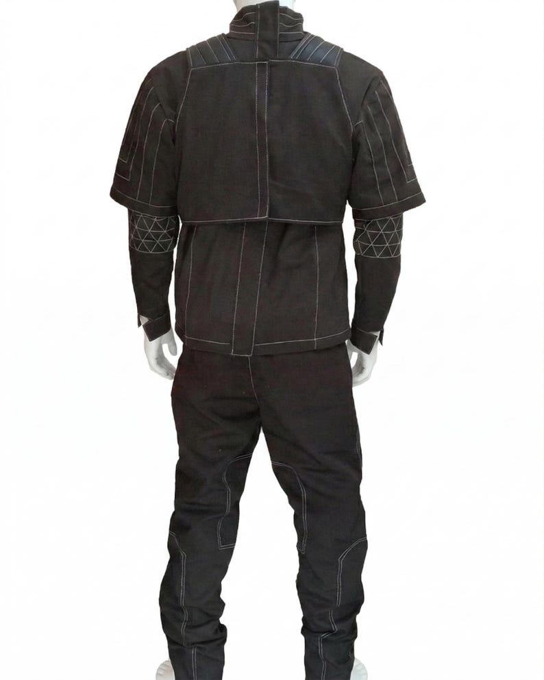 K&ouml;nnte beinhalten: Schwarzes zweiteiliges Outfit mit wei&szlig;en Steppn&auml;hten. Die Jacke hat einen hohen Kragen und kurze &Auml;rmel mit geometrischen Mustern auf den &Auml;rmeln. Die Hose hat verst&auml;rkte Knie. Das Outfit wird auf einer Schaufensterpuppe pr&auml;sentiert.