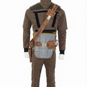 May include: A brown costume displayed on a mannequin. The outfit includes a long-sleeved top, pants, and a utility belt with pouches and a holster. The costume has black accents and a shoulder strap. The mannequin is on a white background.