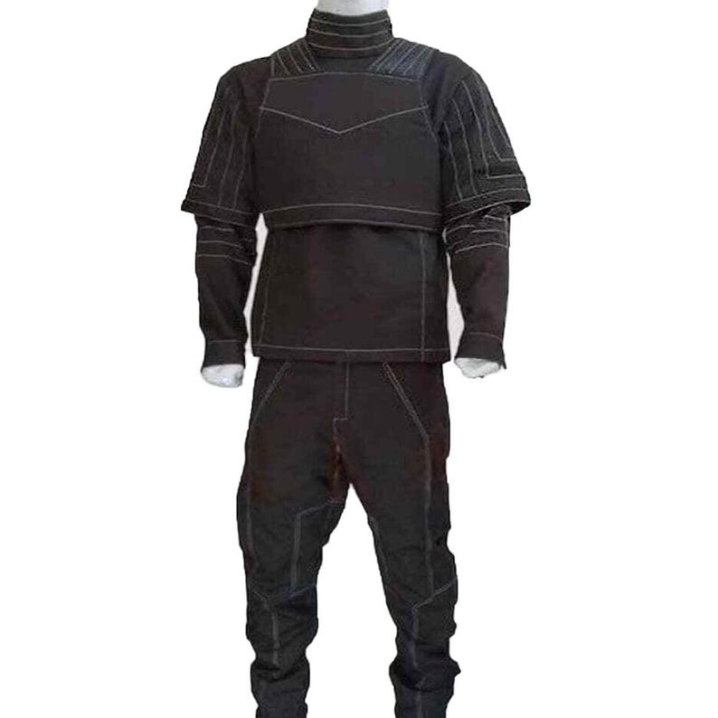 K&ouml;nnte beinhalten: Ein schwarzes zweiteiliges Outfit mit wei&szlig;en N&auml;hten. Das Oberteil hat einen hohen Kragen und kurze &Auml;rmel mit einem geometrischen Design auf der Brust. Die Hose ist ebenfalls schwarz mit wei&szlig;en N&auml;hten und einem einzigartigen Design an den Knien.