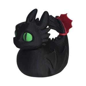 May include: A black dragon figurine with large green eyes and a red wing tip. The dragon is in a sitting position, with a rounded body and a detailed texture. The figurine is a 3D-printed item.