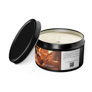 May include: A black metal candle tin with an open lid, revealing a white candle. The label reads "Spa Retreat" with a list of ingredients. The candle has a white wick and a creamy wax. The tin is on a white surface.