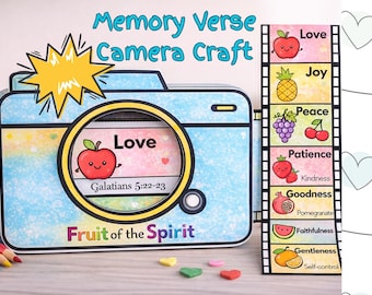 Könnte beinhalten: Ein farbenfrohes Bastelprojekt mit einem Kamera-Design und dem Text "Memory Verse Camera Craft". Das Kameraobjektiv zeigt einen Apfel mit dem Wort "Love" und Galater 5:22-23. Ein Filmstreifen listet die Eigenschaften der "Frucht des Geistes" auf.