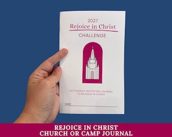 Könnte beinhalten: Ein weißes Journal mit dem Titel 2027 Rejoice in Christ CHALLENGE und einer magentafarbenen Bogengrafik, die eine weiße Kirchenillustration enthält. Der Einbandtext lautet Actionable Invitation Journal to Rejoice in Christ mit einer Namenszeile.