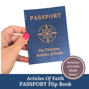 May include: A navy blue passport-style flip book with gold lettering that reads "PASSPORT". The cover features a gold compass rose design and the text "The Thirteen Articles of Faith." The flip book is held by a hand with pink nail polish.