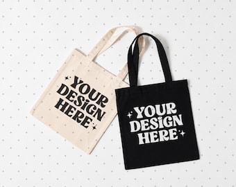 May include: Two tote bags, one beige with black text and one black with white text. Both bags feature the phrase "YOUR DESIGN HERE" in a bold, wavy font, accented by small four-pointed star icons on the left and right sides of the text.