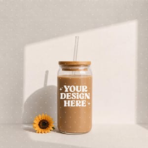 May include: A clear glass tumbler with a bamboo lid and a glass straw, filled with a light brown liquid. The front of the glass features the white text "YOUR DESIGN HERE" in a bold, rounded font, accented by small four-pointed star icons.