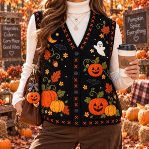 May include: A black knit button-down vest featuring embroidered orange pumpkins, a white ghost, bats, autumn leaves, and yellow flowers. The vest has orange cross-stitch detailing along the V-neck and front placket, worn over a white turtleneck.