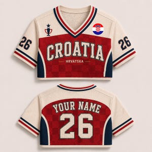 Puede incluir: Una camiseta corta de color crema, rojo y azul marino con el texto CROATIA y HRVATSKA en el frente, el n&uacute;mero 26 en las mangas y la espalda, un icono de trofeo, un emblema circular de la bandera croata y el texto YOUR NAME en la espalda.