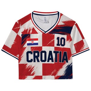 May include: Croatia crop top in red and white checkered pattern with the word "CROATIA" in navy blue. Features the Croatian flag and the number "10". The top has a V-neck and navy blue trim.