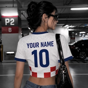 May include: White crop top with blue trim and the number 10 in blue. The shirt has the text "YOUR NAME" above the number. The bottom of the shirt has a red and white checkered pattern.