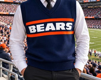 May include: A navy blue V-neck sweater vest featuring the word BEARS in white block letters, positioned between two horizontal orange stripes. The vest is worn over a crisp white long-sleeved button-down shirt with a black necktie.