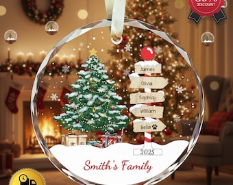 May include: A clear, faceted Christmas ornament with a festive scene inside. It features a snow-covered Christmas tree, gifts, and a signpost with family names. The ornament is inscribed with "Smith's Family" and the year 2025.