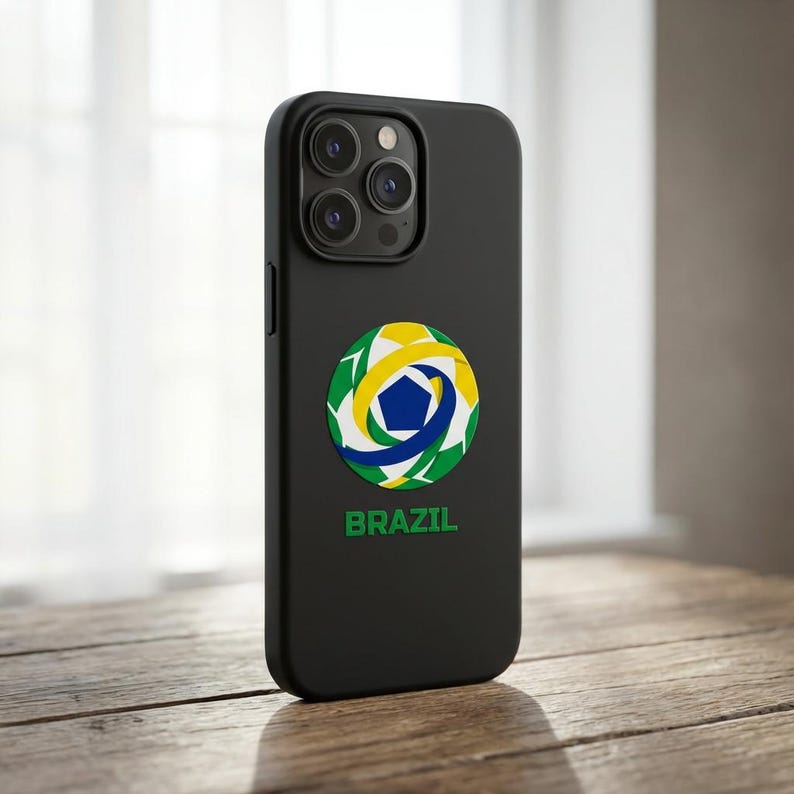 May include: Black phone case with a Brazil soccer ball design. The case features a circular emblem with green, yellow, blue, and white colors, and the word "BRAZIL" in green text below the emblem.