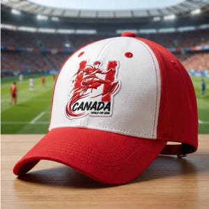 Może przedstawiać: Czapka bejsbolowa w kolorze czerwono-białym z grafiką piłkarza kopiącego piłkę, z napisem "CANADA" i "WORLD CUP 2016" z przodu. Czapka ma zakrzywiony daszek i regulowany pasek.
