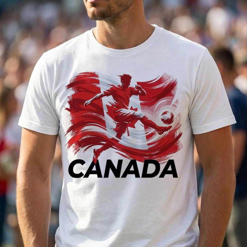 Puede incluir: Camiseta blanca con un gr&aacute;fico rojo y blanco de un jugador de f&uacute;tbol pateando un bal&oacute;n, sobre un dise&ntilde;o estilizado de la bandera canadiense. La palabra "CANADA" est&aacute; impresa en negro debajo.