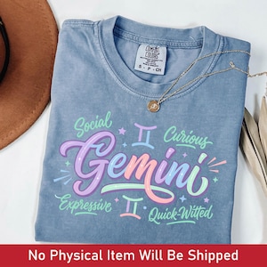 May include: A blue Comfort Colors t-shirt with the word "Gemini" in colorful script, along with the words "Social", "Curious", "Expressive", and "Quick-Witted". A gold necklace with a pendant is draped across the shirt.