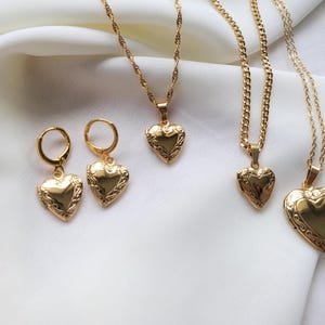 May include: Gold-colored jewelry set featuring heart-shaped lockets and earrings. The set includes two pairs of earrings and three necklaces with different chain styles. The heart pendants and earrings have an ornate, detailed design.