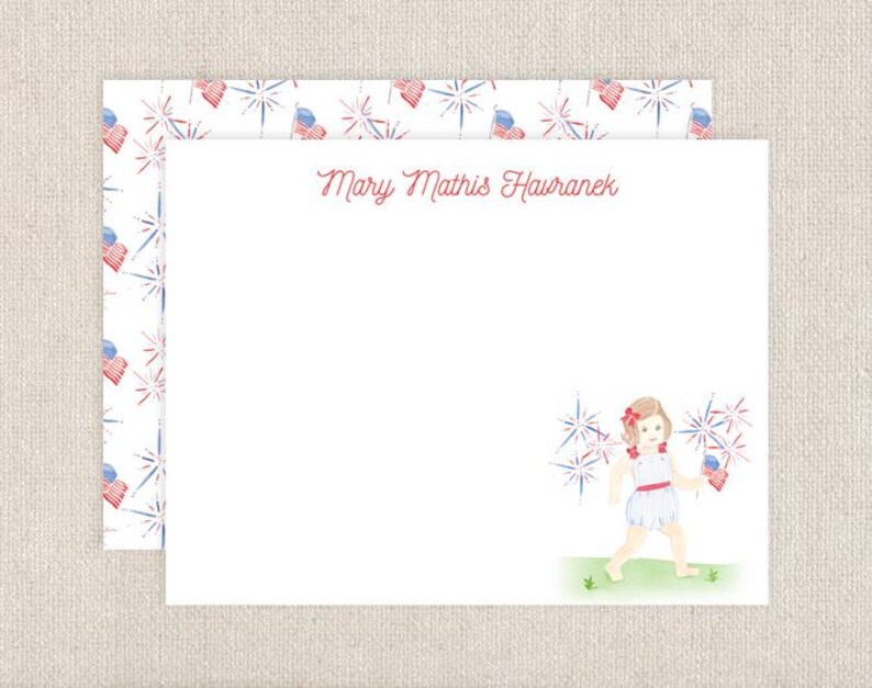 Pode incluir: Um cart&atilde;o branco com uma borda de padr&atilde;o de fogos de artif&iacute;cio vermelho, branco e azul. O cart&atilde;o tem o texto "Mary Mathis Havranek" impresso em vermelho cursivo. O cart&atilde;o apresenta uma ilustra&ccedil;&atilde;o de aquarela de uma menina com um vestido vermelho, branco e azul segurando fogos de artif&iacute;cio.