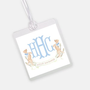 May include: Clear, square luggage tag with a white background. The tag features a light blue monogram, two watercolor dogs, and the name "HOLLIS HAVRANEK" in a banner. A clear ribbon is attached for hanging.