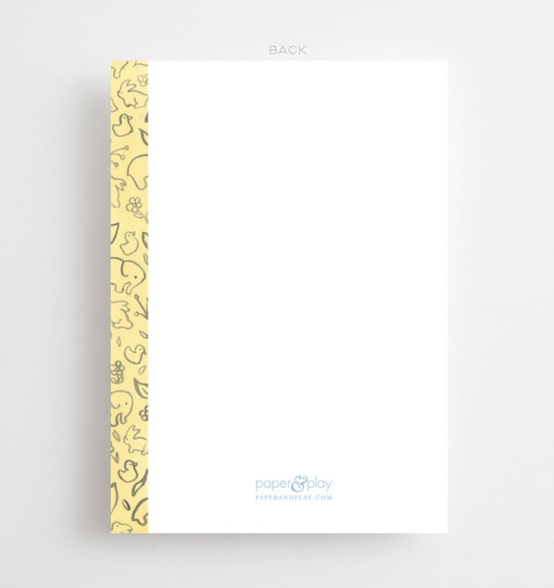 Pu&ograve; includere: Un biglietto bianco con un bordo giallo con un motivo di piccoli animali e fiori. Il testo "paper & play" e "paperandplay.com" &egrave; stampato in blu nella parte inferiore del biglietto.